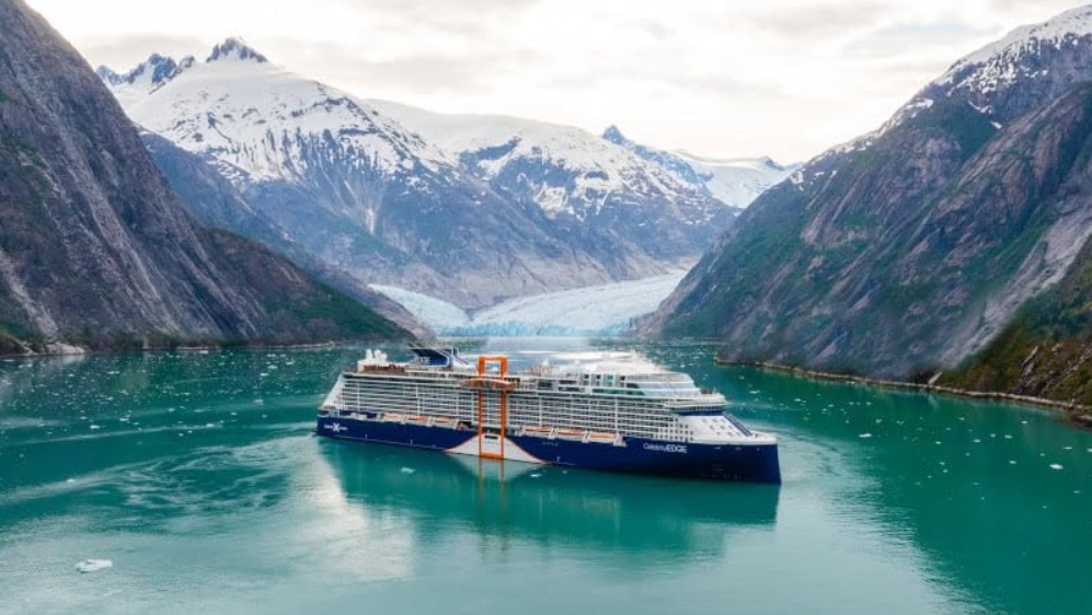 Cruise ship at rest in a glacial Alaskan fjord below snow-covered mountains
