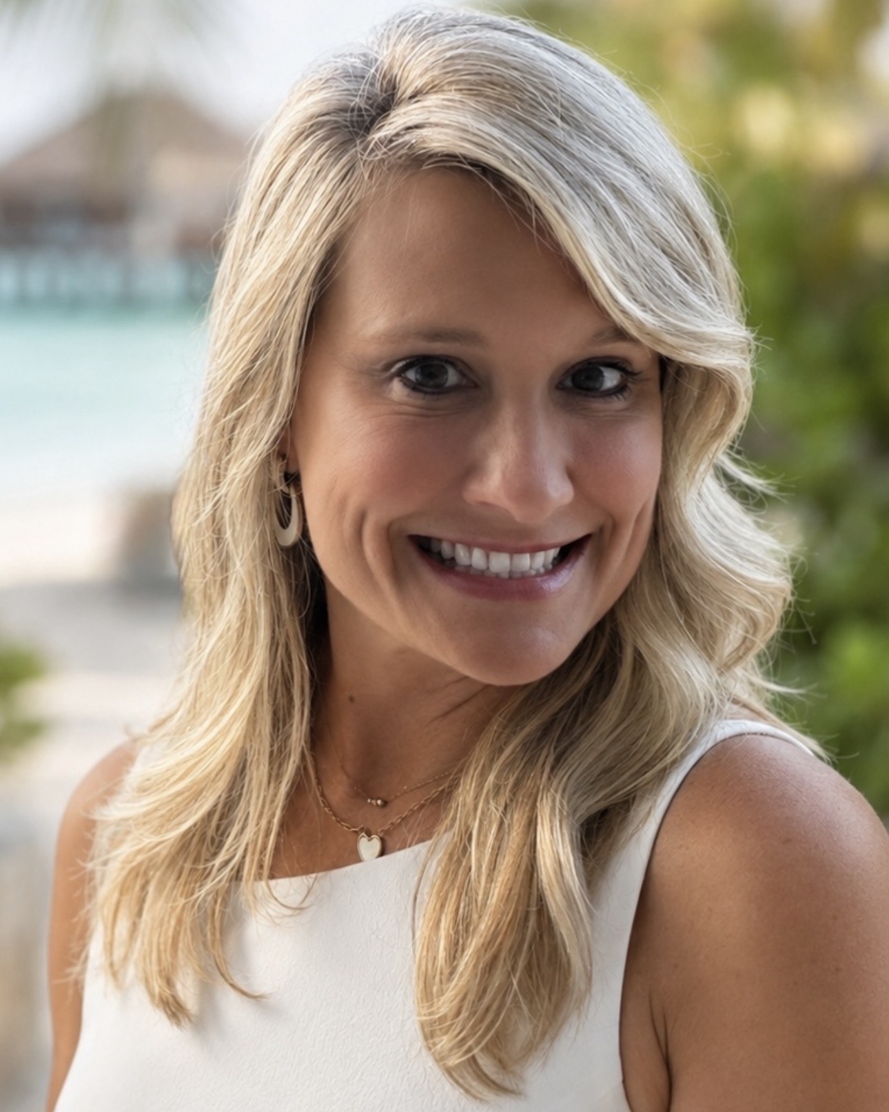 Christy Benton smiling on a beach walkway beside turquoise water